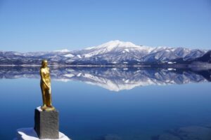 雄大な湖を背景に佇む金色のたつこ像(田沢湖,秋田)